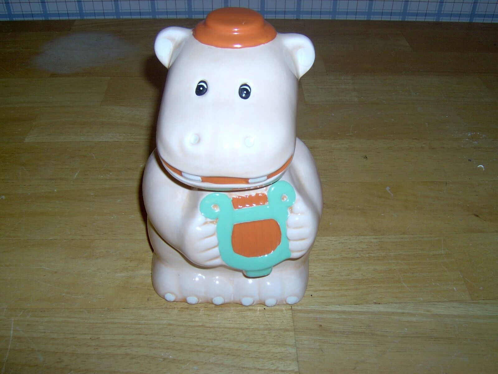 ORANGE HARP PLAYING CERAMIC HIPPO BANK WITH STOPPER.